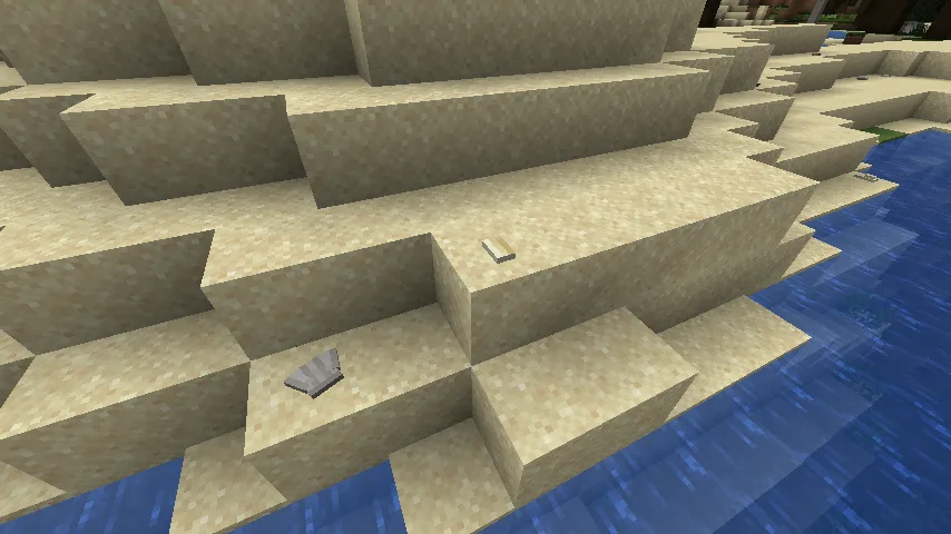 Морские ракушки и камни на песчаном пляже в Minecraft.